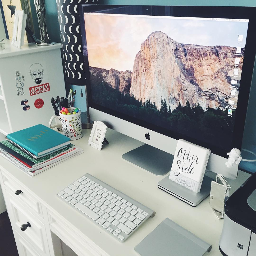 Clean desk with mac computer books and decorative figurines